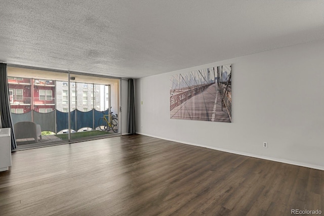 unfurnished room with expansive windows, a textured ceiling, baseboards, and wood finished floors