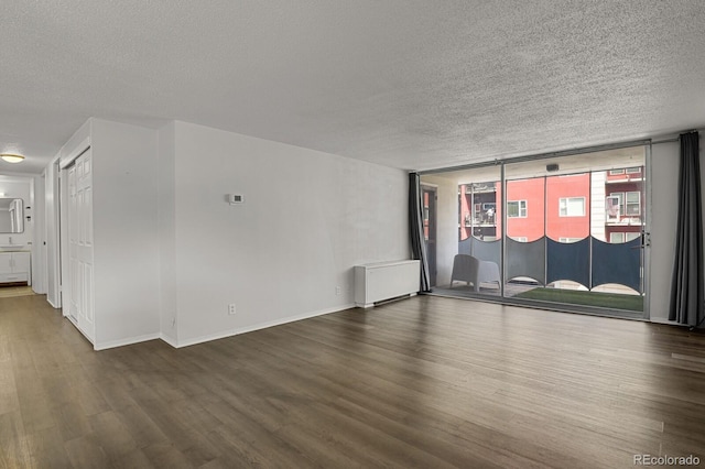 unfurnished room with a textured ceiling, baseboards, and wood finished floors