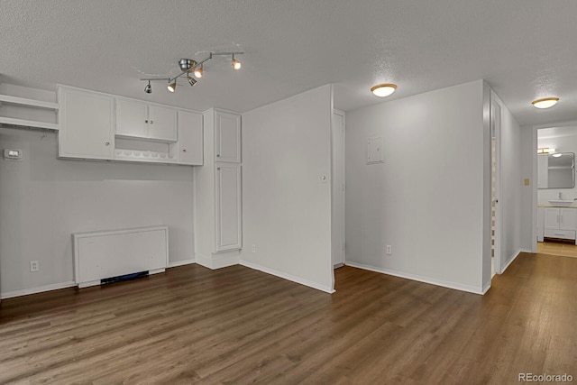 unfurnished room with a textured ceiling, wood finished floors, and baseboards