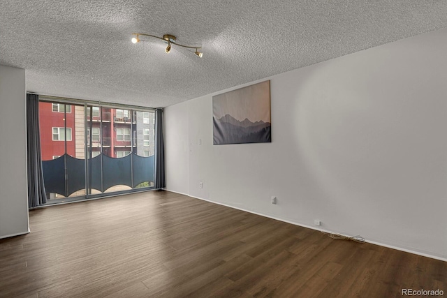 unfurnished room with a textured ceiling, a wall of windows, and wood finished floors