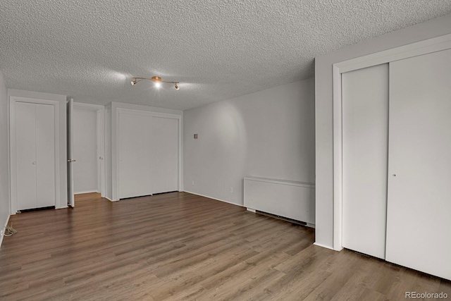 unfurnished bedroom with a textured ceiling and wood finished floors