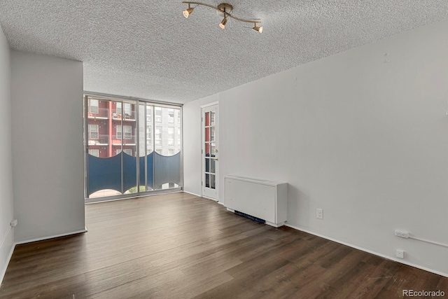 empty room featuring a textured ceiling, expansive windows, and wood finished floors