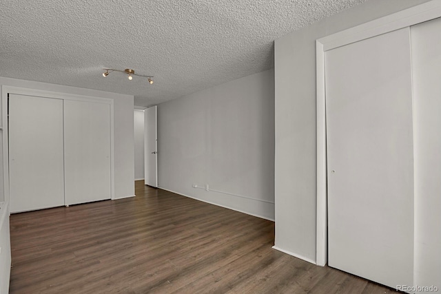 unfurnished bedroom featuring a textured ceiling, dark wood-type flooring, and a closet