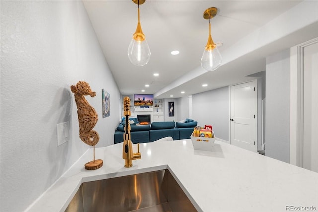 2153 Mountain Iris Dr, Erie, CO 80516 - kitchen featuring recessed lighting, a lit fireplace, light countertops, hanging light fixtures, and open floor plan