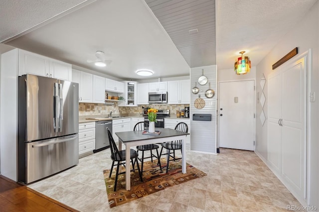 kitchen featuring a sink, light countertops, appliances with stainless steel finishes, white cabinetry, and backsplash