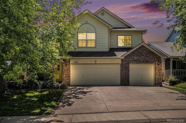 11868 W Progress Ave, Littleton, CO 80127 - view of front of home with driveway, brick siding, an attached garage, roof with shingles, and a front yard