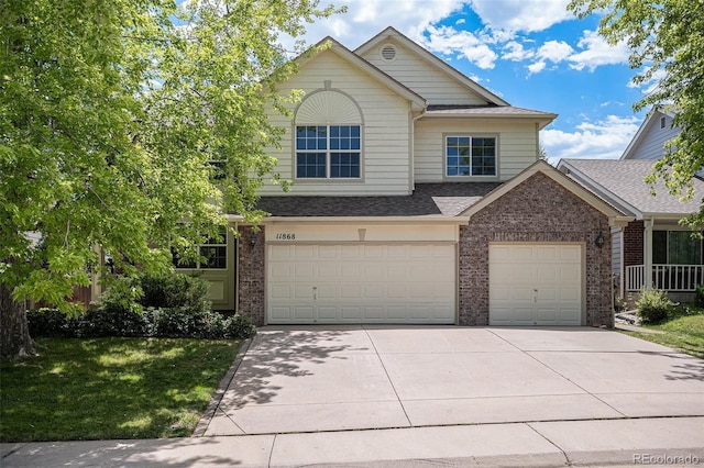 11868 W Progress Ave, Littleton, CO 80127 - view of front of property with brick siding, driveway, an attached garage, a shingled roof, and a front lawn