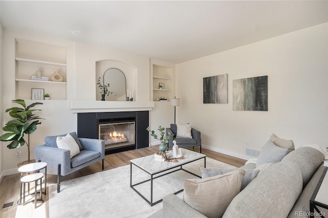 11868 W Progress Ave, Littleton, CO 80127 - living area with built in shelves, a glass covered fireplace, and wood finished floors