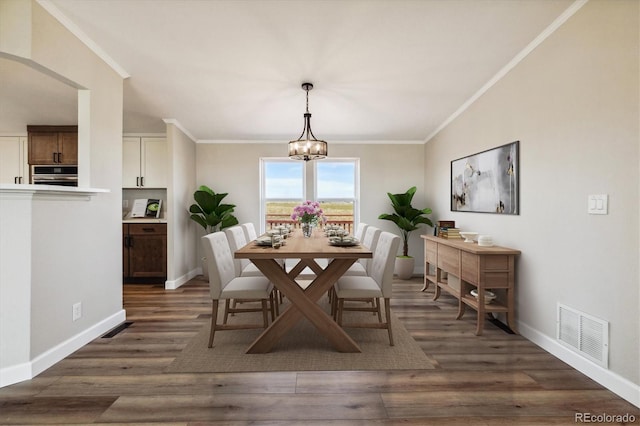 dining room featuring crown molding, dark wood-type flooring, and a notable chandelier