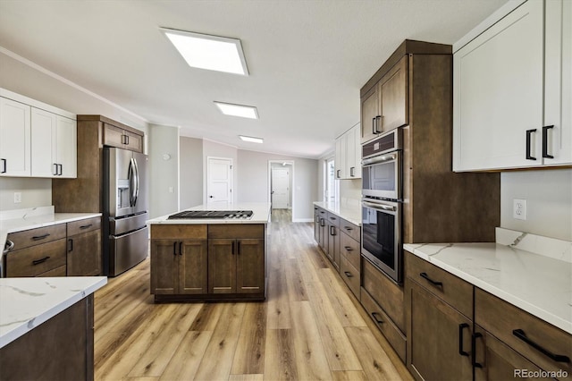 kitchen with dark brown cabinetry, white cabinetry, lofted ceiling, and appliances with stainless steel finishes