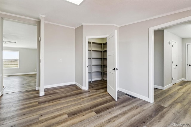 unfurnished bedroom with dark hardwood / wood-style floors, a spacious closet, and crown molding