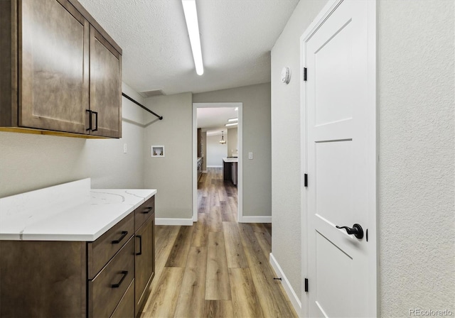 interior space featuring light hardwood / wood-style floors, cabinets, a textured ceiling, and washer hookup