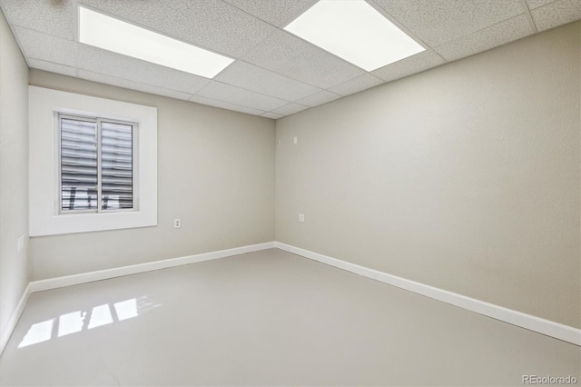 unfurnished room featuring concrete floors and a drop ceiling