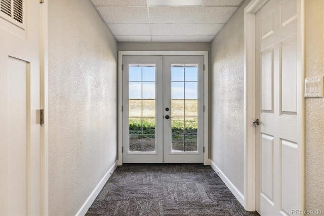 entryway with a drop ceiling, dark carpet, a healthy amount of sunlight, and french doors