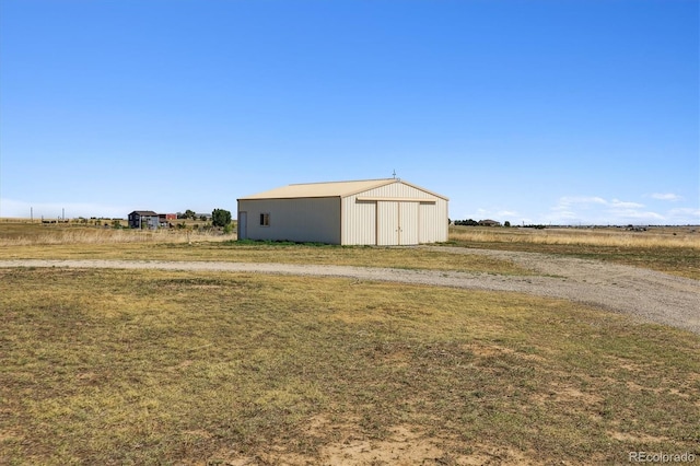 view of outbuilding with a rural view and a yard