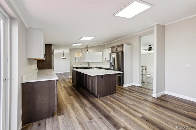 43343 E Arkansas Pl, Bennett, CO 80102 - kitchen with stainless steel fridge with ice dispenser, light countertops, baseboards, crown molding, and a center island