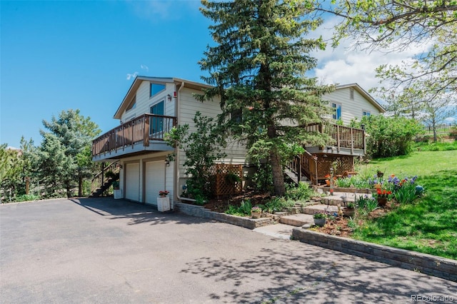 view of front of property featuring stairs, a wooden deck, driveway, and an attached garage