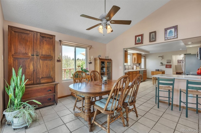 dining area with light tile patterned floors, ceiling fan, high vaulted ceiling, and baseboards