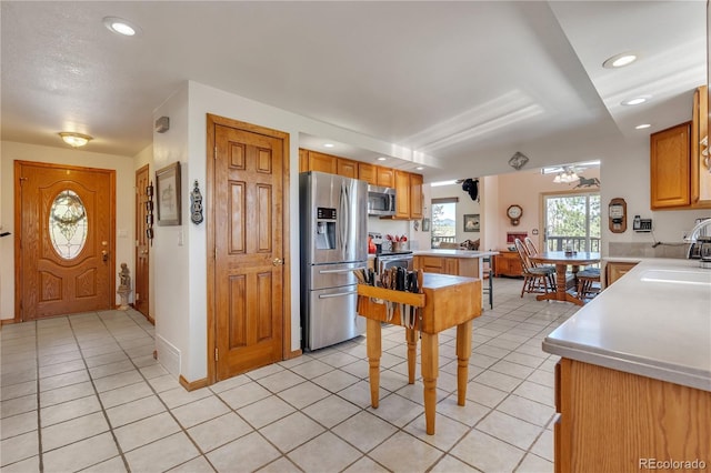 kitchen with appliances with stainless steel finishes, a sink, light countertops, light tile patterned floors, and recessed lighting