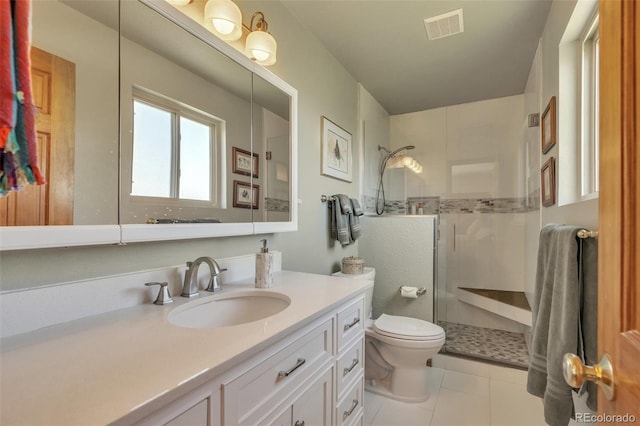 bathroom with a tile shower, tile patterned flooring, vanity, and toilet