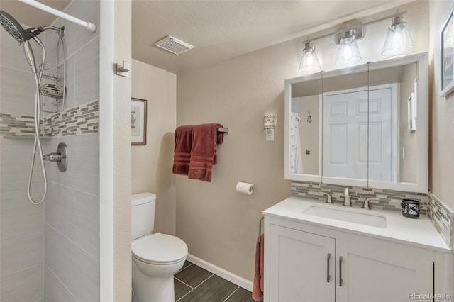 bathroom with toilet, a tile shower, vanity, tasteful backsplash, and wood finished floors