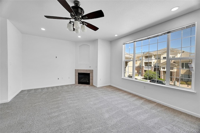 unfurnished living room featuring a tiled fireplace, carpet, and ceiling fan