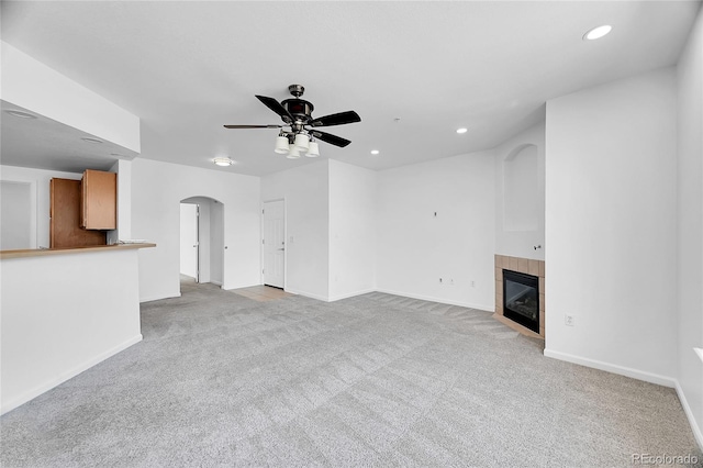 unfurnished living room featuring a fireplace, light colored carpet, and ceiling fan