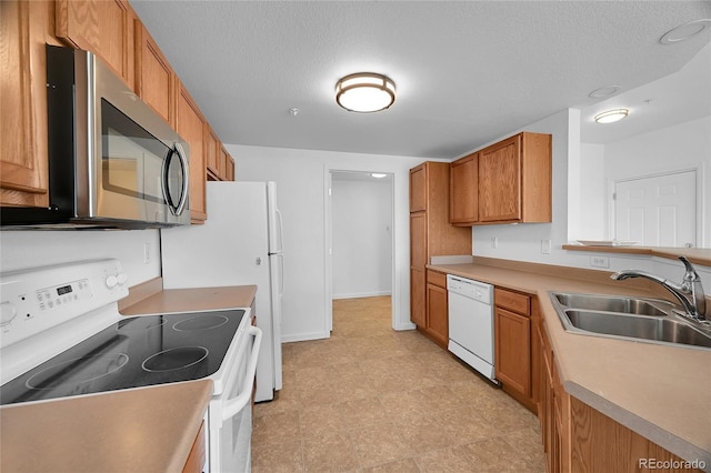 kitchen with sink, a textured ceiling, light tile patterned floors, and white appliances