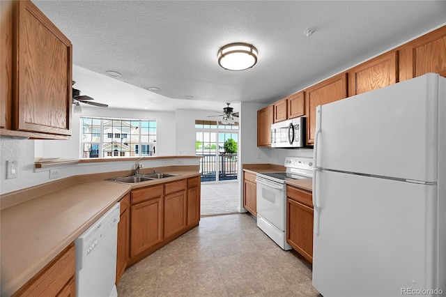 kitchen featuring light tile patterned flooring, ceiling fan, white appliances, sink, and a textured ceiling