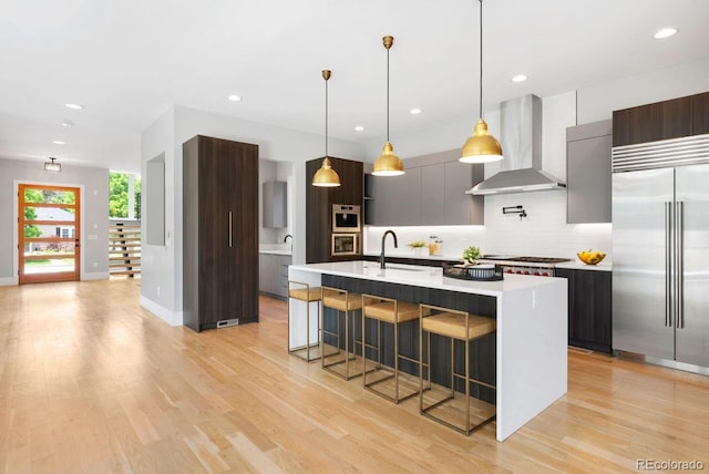 1500 S Elizabeth St, Denver, CO 80210 - kitchen featuring built in refrigerator, wall chimney range hood, modern cabinets, light countertops, and a kitchen breakfast bar