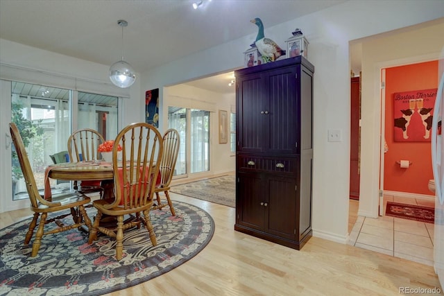 dining space with light wood-type flooring and baseboards