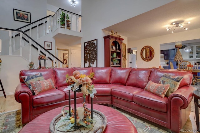 living room with a high ceiling, stairway, and light wood-style floors