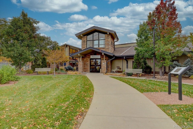 view of front facade with stone siding and a front lawn