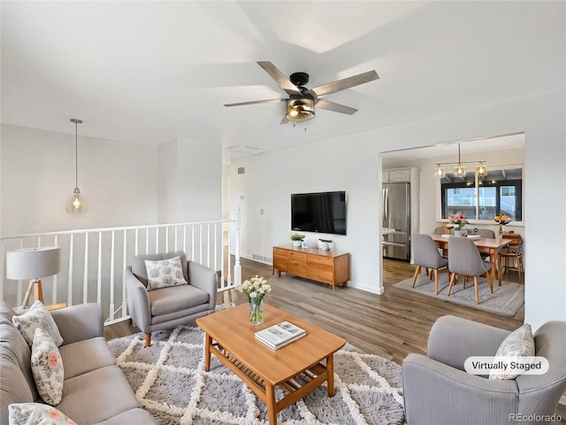 living room with hardwood / wood-style floors and ceiling fan with notable chandelier