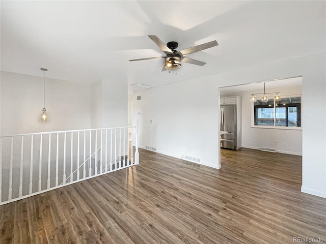 spare room with dark hardwood / wood-style floors and ceiling fan with notable chandelier