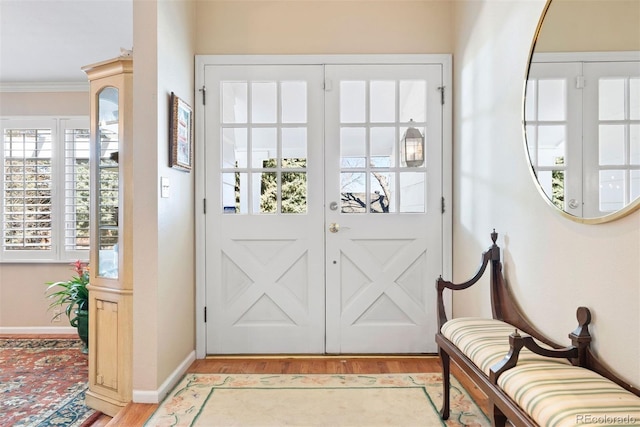 entrance foyer with light wood-type flooring, baseboards, and ornamental molding