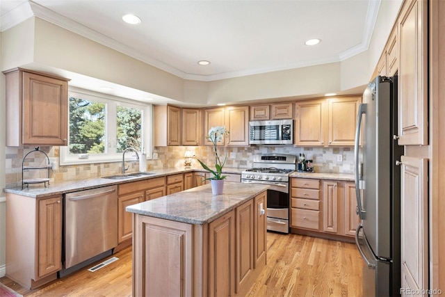 kitchen with light wood-style flooring, appliances with stainless steel finishes, light stone counters, ornamental molding, and a sink