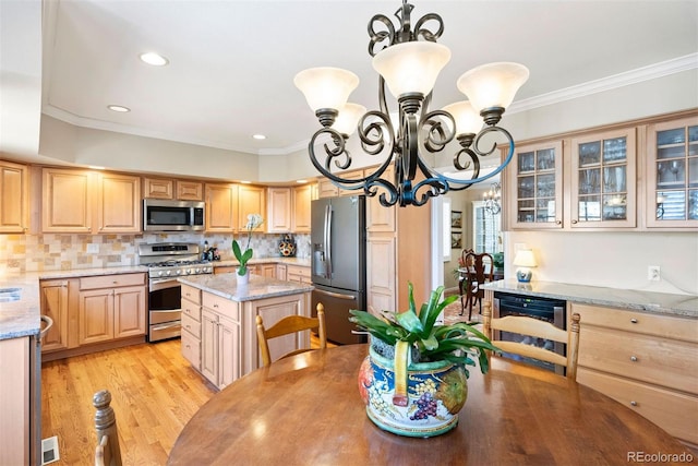 kitchen featuring ornamental molding, stainless steel appliances, wine cooler, and a notable chandelier