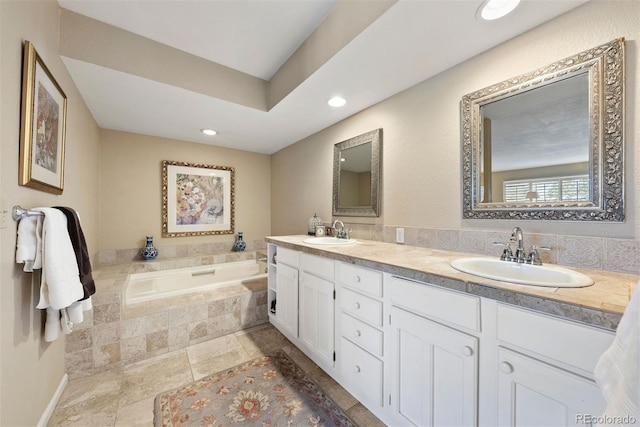 bathroom featuring recessed lighting, a garden tub, a sink, and double vanity