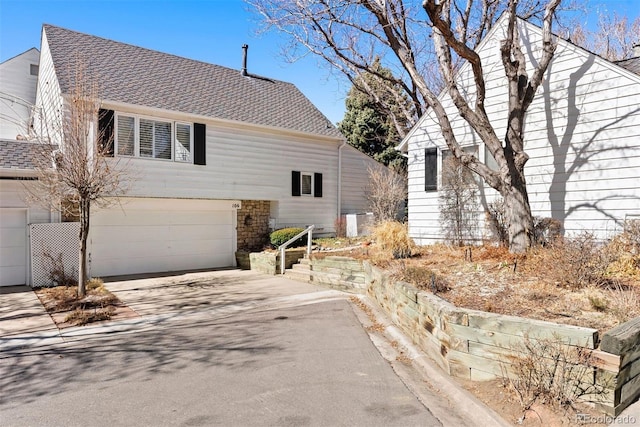 view of front of home with driveway, a garage, and roof with shingles