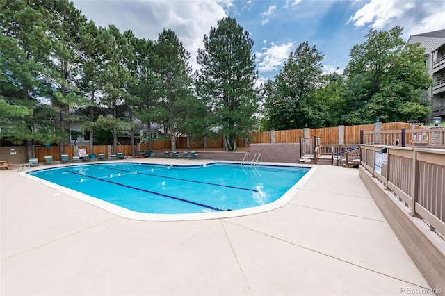 community pool with a patio area and fence