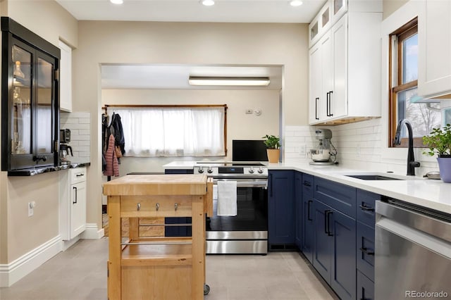 kitchen featuring sink, white cabinets, decorative backsplash, stainless steel appliances, and blue cabinetry