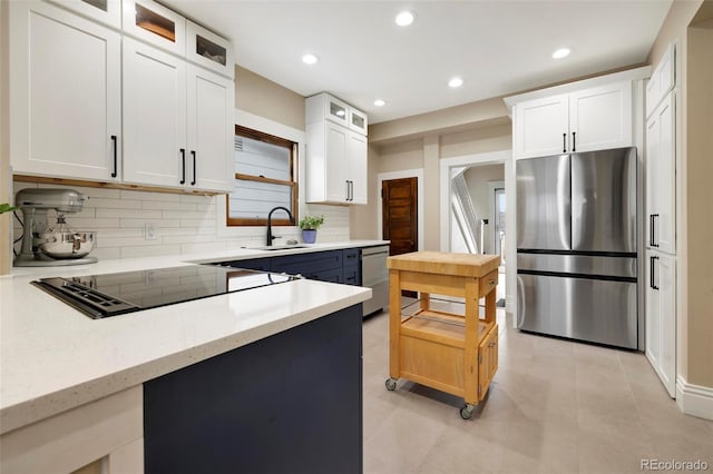 kitchen featuring tasteful backsplash, white cabinetry, appliances with stainless steel finishes, and sink