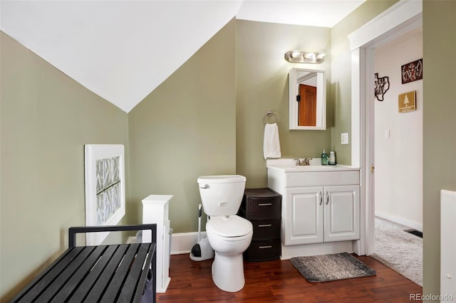 bathroom with hardwood / wood-style flooring, lofted ceiling, toilet, and vanity