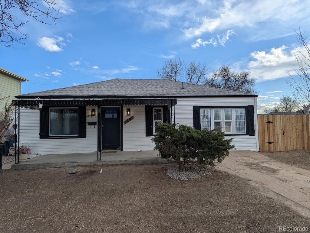 view of front of property featuring covered porch, roof with shingles, and fence