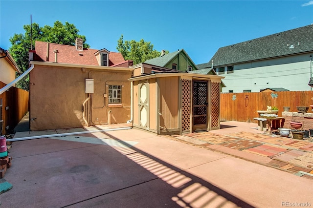 back of house featuring a patio and an outbuilding