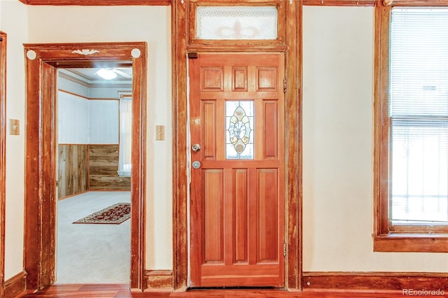 carpeted foyer featuring crown molding