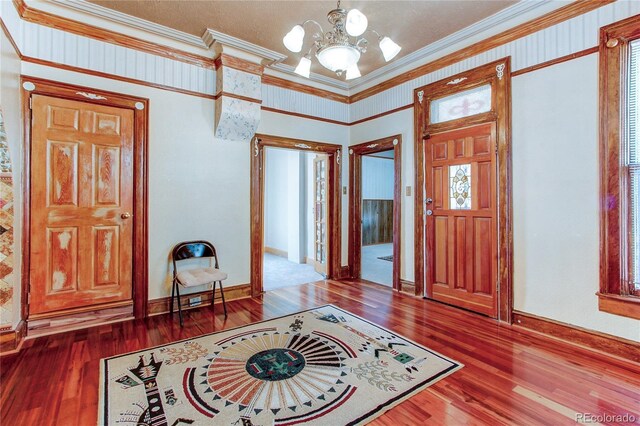 entryway featuring a chandelier, ornamental molding, and hardwood / wood-style flooring