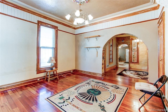 foyer entrance with a textured ceiling, ornamental molding, hardwood / wood-style floors, and an inviting chandelier