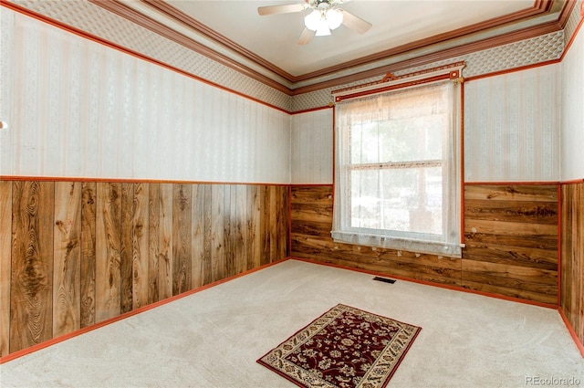 carpeted spare room with ceiling fan, crown molding, and a healthy amount of sunlight